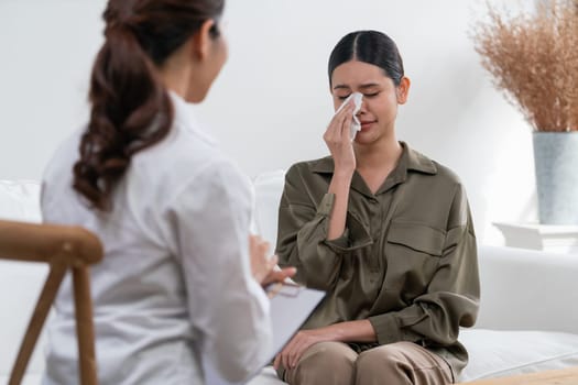 Sad PTSD woman patient in uttermost therapy for mental health with psychologist, depression or grief after life failure. Frustrated trauma young woman talking to a psychologist about emotion in clinic