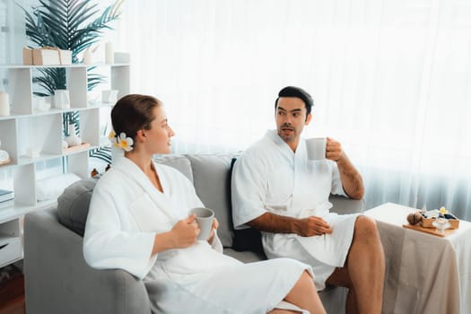 Beauty or body treatment spa salon vacation lifestyle concept with couple wearing bathrobe relaxing with drinks in luxurious hotel spa or resort room. Vacation and leisure relaxation. Quiescent