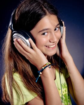 Cute girl with headphones smiling. Dark background.