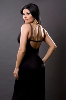 pretty brunette woman wearing black dress on grey