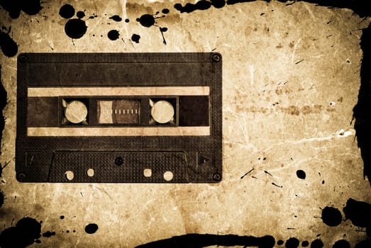 Grungy audio cassette on old paper background