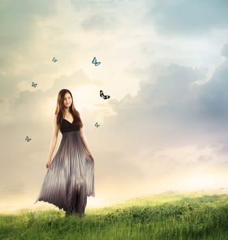 Young woman in a beautiful silver dress in a fantasy landscape with butterflies
