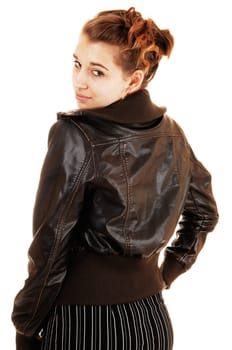 A young pretty woman in a striped black dress and a brown leather jacket standing from the back and looking over her shoulder, over white.