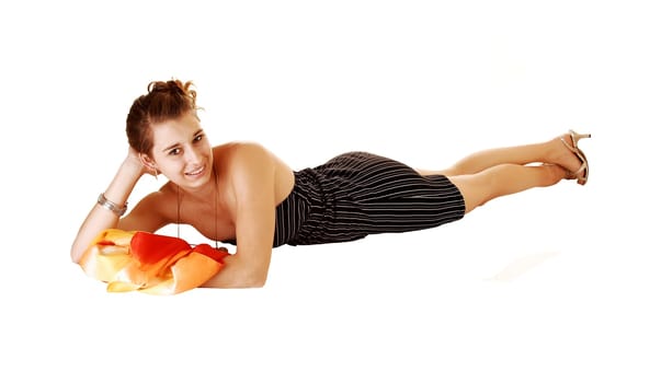 A pretty and young woman in a black dress with stripes on lying in frond on her stomach for white background with a colourful scarf.