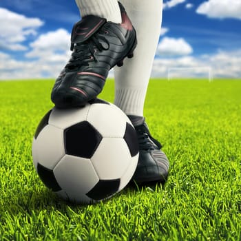 Football and feet of a player in casual pose on an open playing field