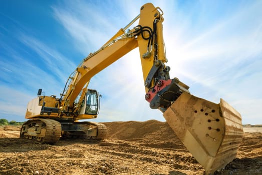 Large excavator with sun and blue sky in background