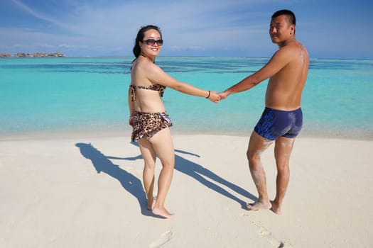 happy young asian couple enjoying summer and have on beautiful white sand beach