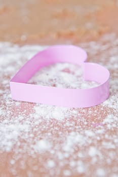 Closeup of heart shaped gingerbread biscuit cutter and dough