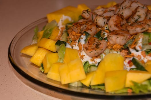 Glass plate with salad of greens, mango and shrimp