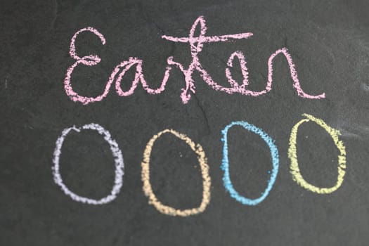 Closeup of four Easter egg shaped chalk drawings and text on dark background