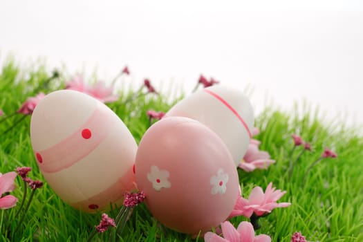 Three pink Easter eggs on a green meadow