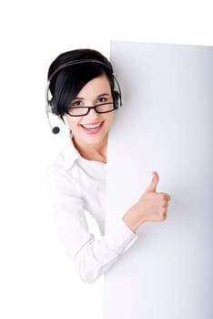 Pretty young call center worker wearing a headset and holding blank sign board