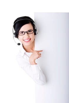 Pretty young call center worker wearing a headset and holding blank sign board