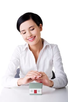 Beautiful young businesswoman with house model over white - real estate loan concept