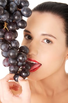 Beautiful sensual brunette eating grapes, isolated on white background