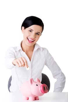Happy businesswoman putting an euro coin into a piggy bank isolated on white background