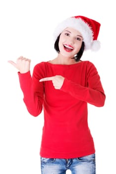 Beautiful smiling christmas santa woman pointing on side showing copyspace. Isolated on white background.