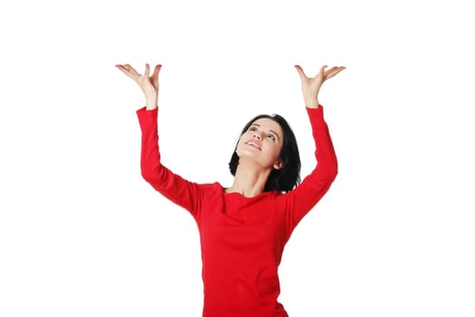Smiling young woman is holding something abstract above her head. Happy girl with raised hands. Isolated on white background.