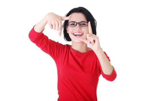 Smiling woman wearing red blouse is showing frame by hands. Happy girl with face in frame of palms. Isolated on white background.