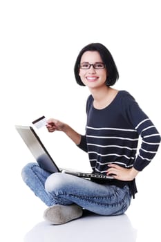 Woman with a laptop and a credit card, sitting on the floor, isolated on white