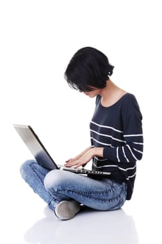 A young thoughtful woman with a laptop sitting isolated on white background