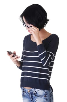 Pretty student standing and reading sms from her cell phone ( smartphone ). Isolated on white.