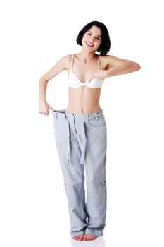 Young fit woman showing how much weight did she lost. Isolated on white