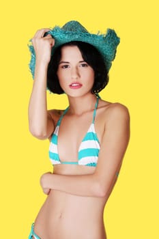 Sexy brunette woman posing in bikini, over yellow background