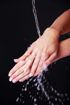 Water falling on female hands, over black background