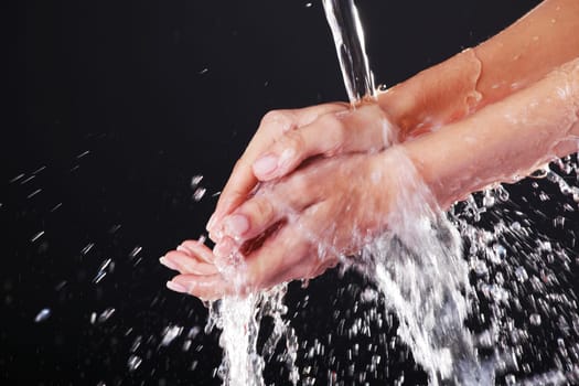 Water falling on female hands, over black background