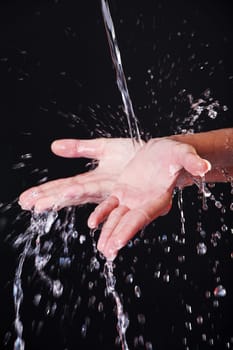 Water falling on female hands, over black background