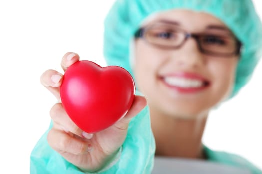 Smiling female doctor or nurse in surgical clothes holding red heart