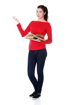 Happy young woman (student or teacher) with book in hand showing on copy space. Isolated on white.