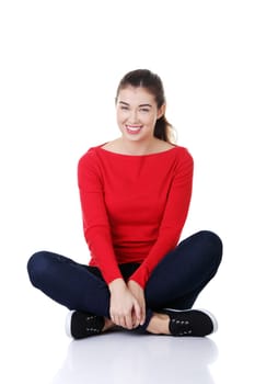 Young beautiful woman in casual clothes sitting on floor, isolated on white