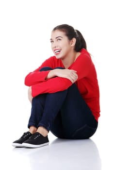 Young beautiful woman in casual clothes sitting on floor, isolated on white