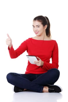 Young pretty woman sitting and working on tablet computer, isolated on white