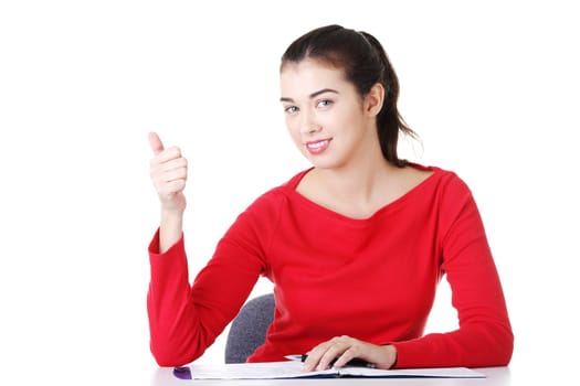 Young woman at the desk gesturing OK , isolated on white