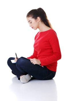 Studying thoughtful young woman reading her notebook for school.
