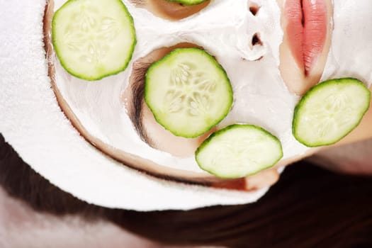 Young woman with cucumber slices on the face in a spa saloon