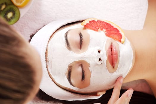 Attractive young woman with fruit mask on a face at spa saloon