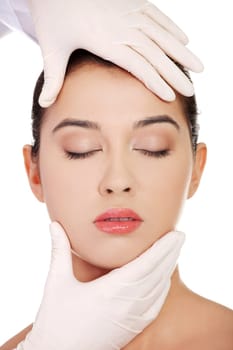 Plastic surgery concept. Doctor hands in gloves touching the beautiful woman face. Isolated on white