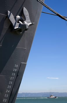 Vertical Composition of Moored Ship Bow and Anchor Tugboat Passing in Bay Underneath