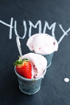 Closeup of strawberry ice cream and strawberry with chalk written word on dark background