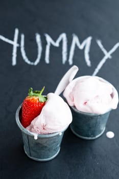 Closeup of strawberry ice cream and strawberry with chalk written word on dark background