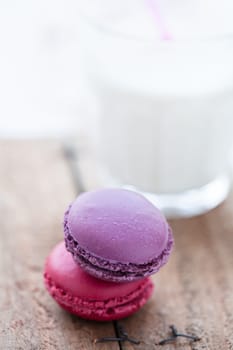 Closeup of two macaroons and glass milk on wooden table