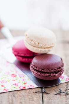 Closeup of three different flavoured macaroons on cake server on wooden table