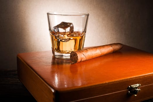 Whiskey and cigar on wooden box close up
