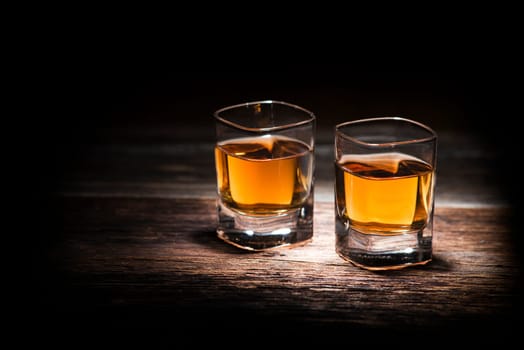 Glass of whiskey on wooden background close up
