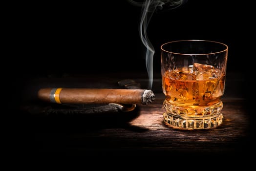 Whiskey and cigar on wooden background close up