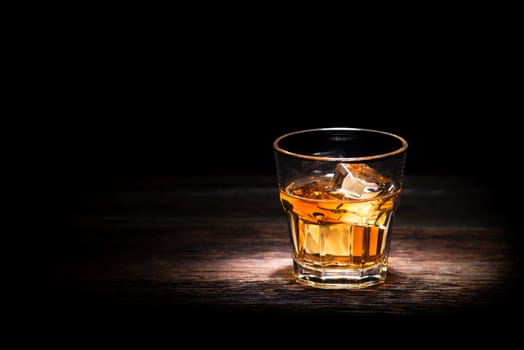 Glass of whiskey on wooden background close up
